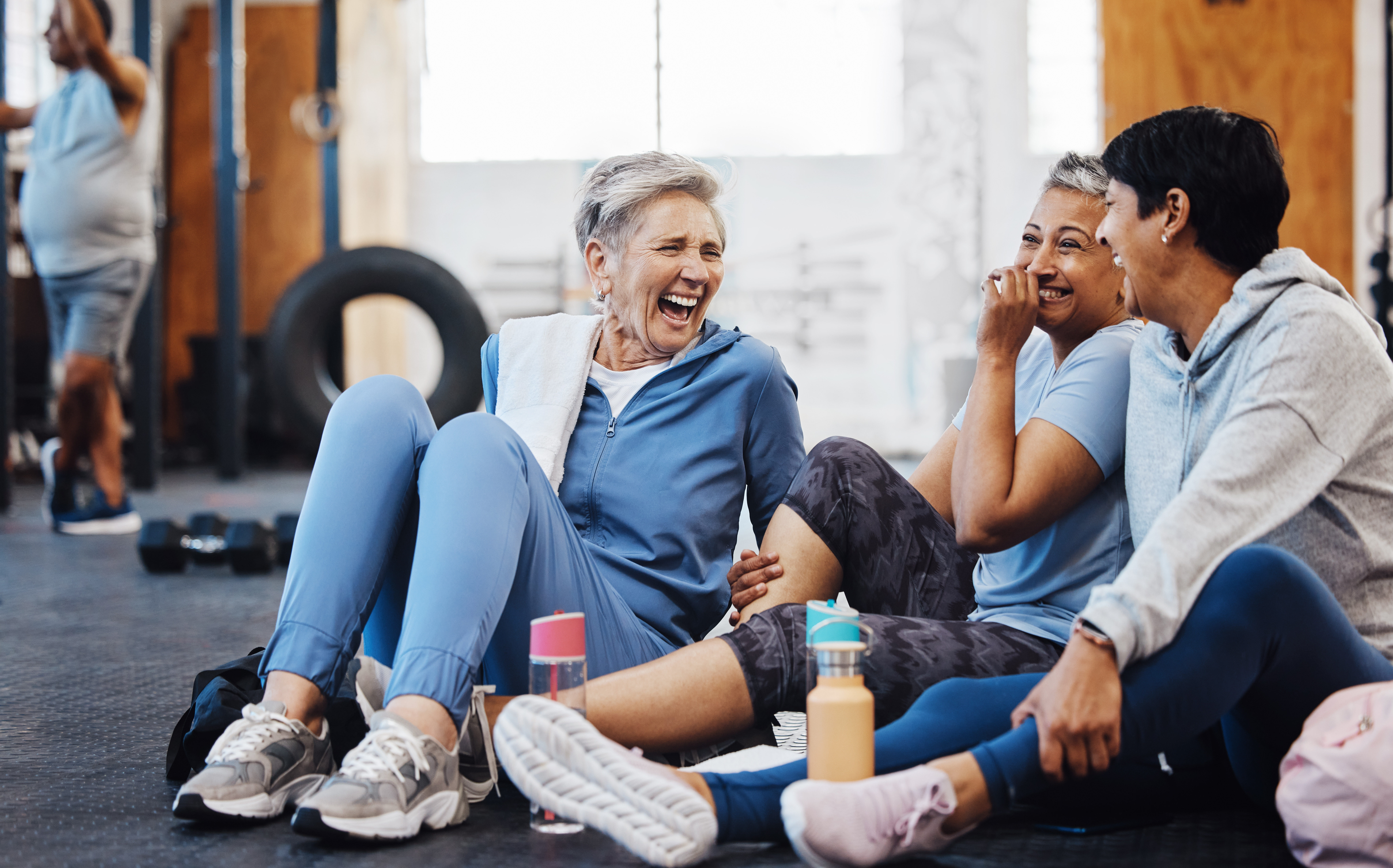 Three women in tracksuits at gym all laughing