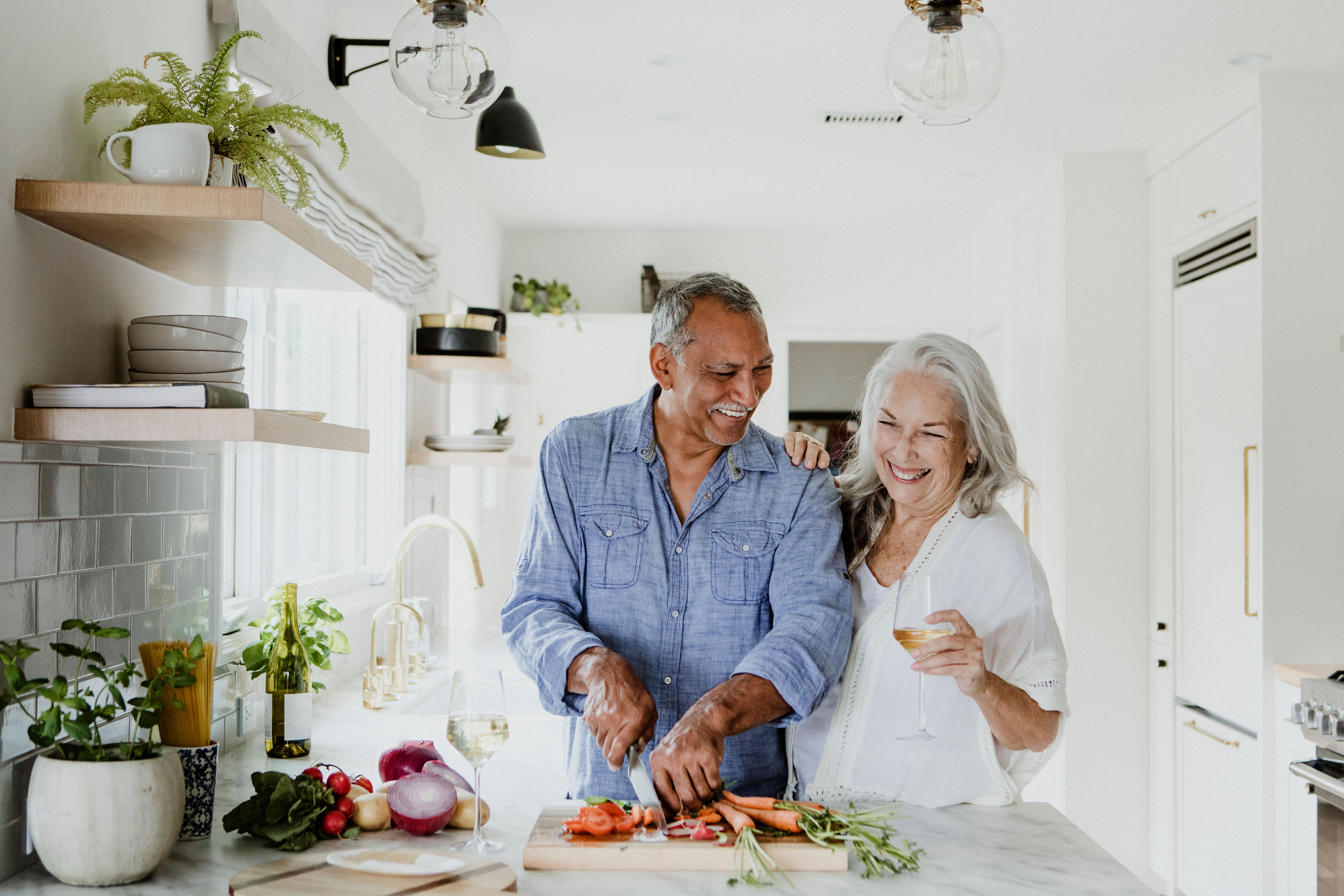 Older couple in kitchen with man chopping fresh vegetables