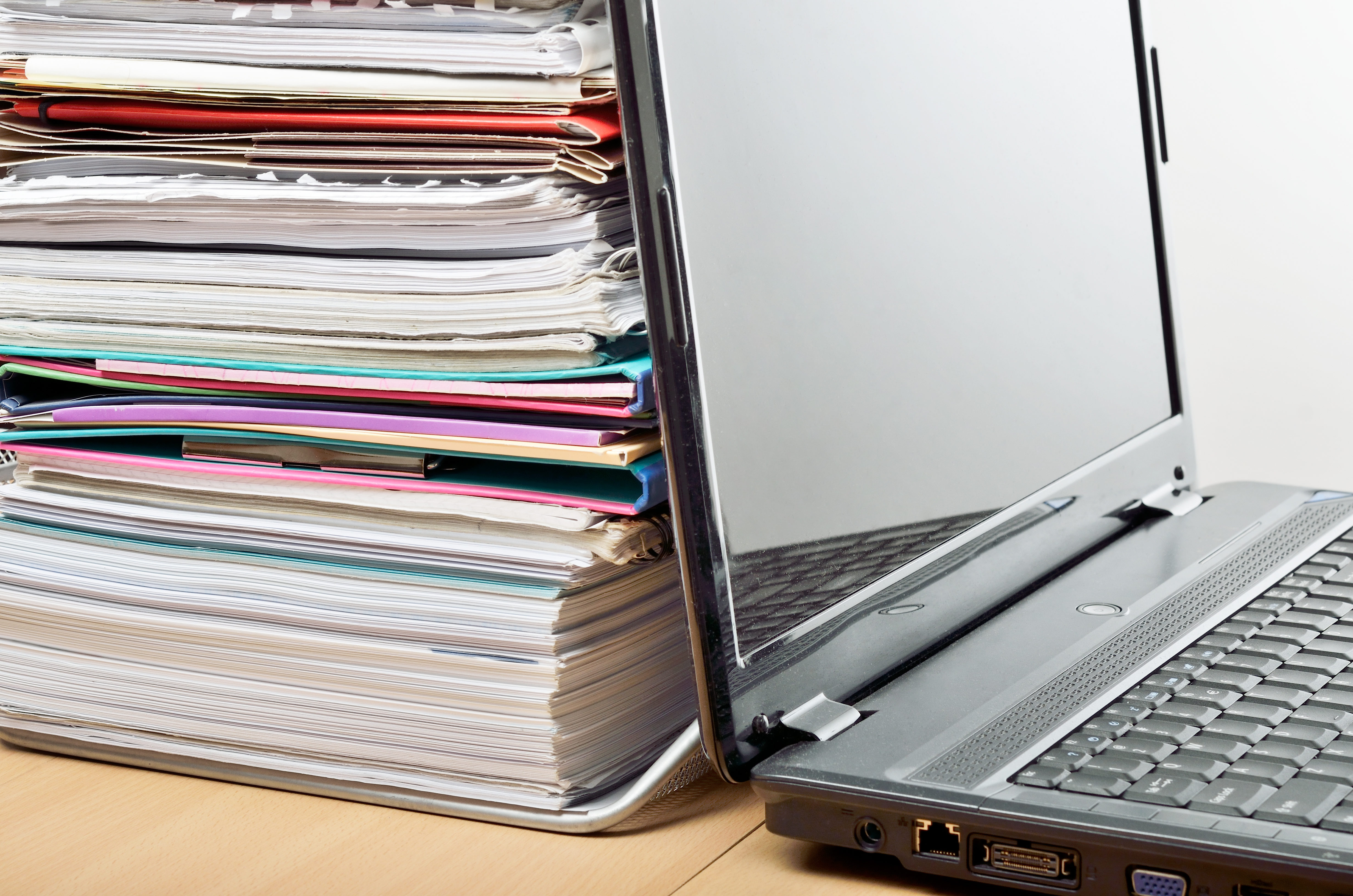 Laptop computer beside a pile of books and leaflets