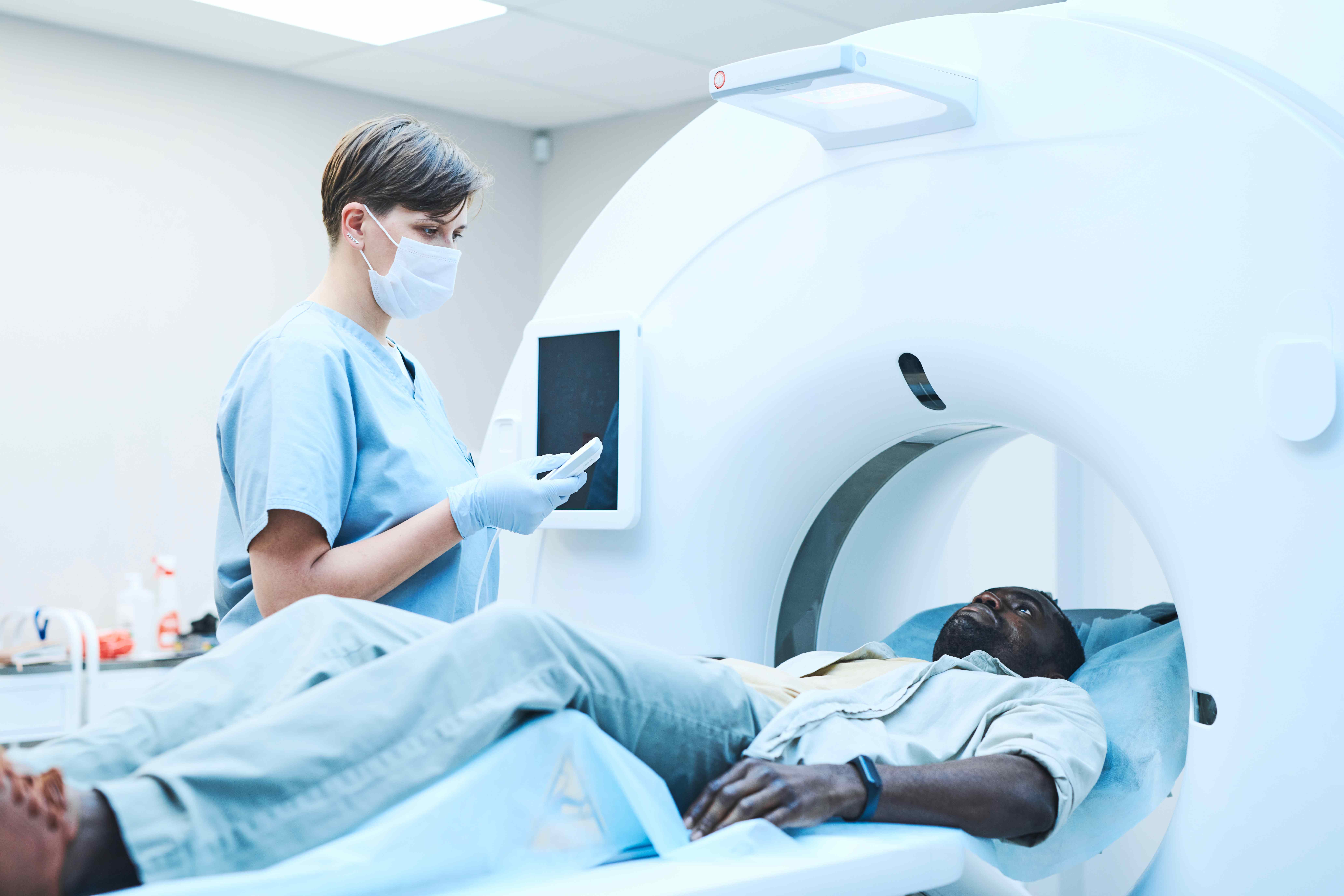 Black man in MRI scanner talking to radiographer