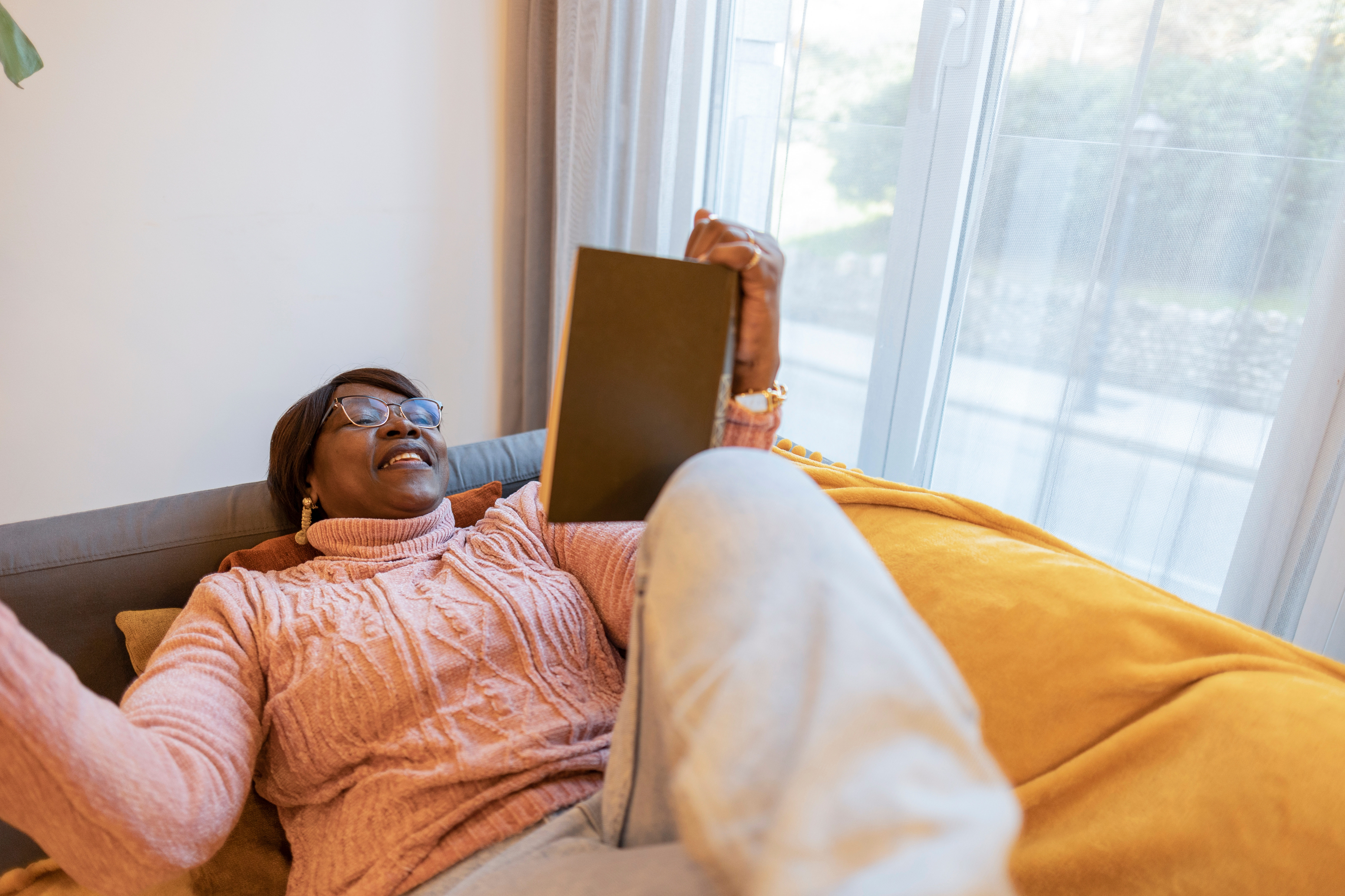 Woman relaxing on sofa with a book