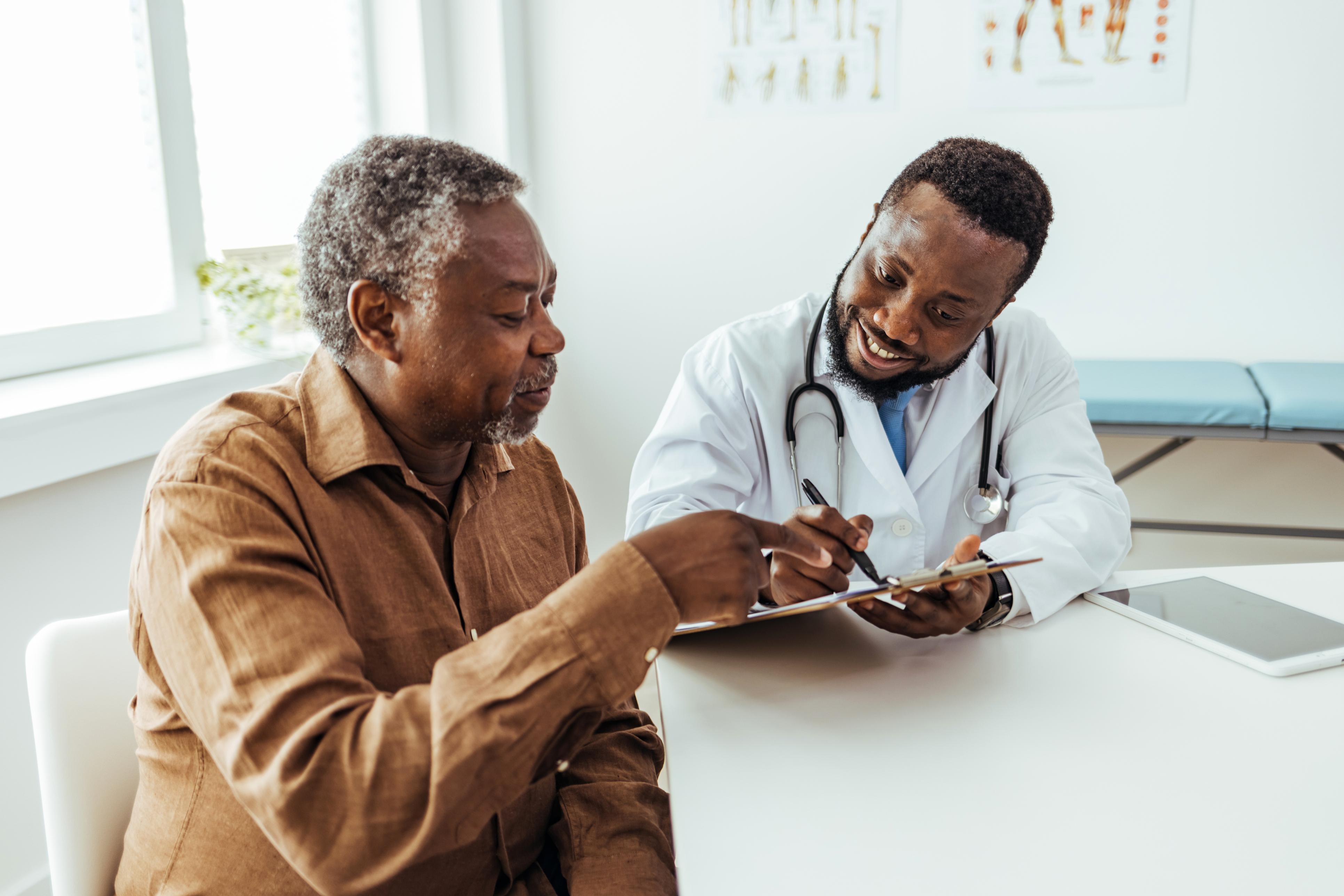 Older Black man talking to Black Doctor in a white coat